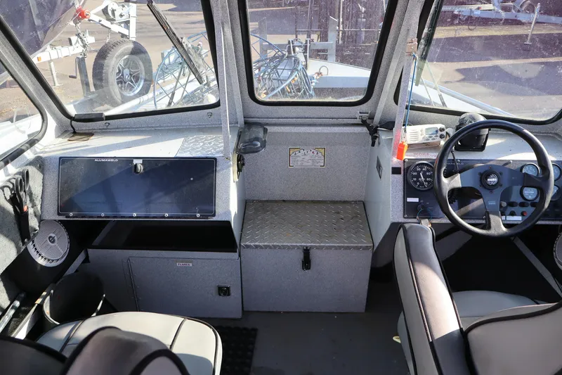 Slide: The Image of Interior of a 2000 Alumaweld Intruder Outboard 20 boat, featuring steering controls and dashboard. - 6