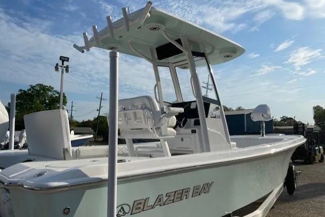 Slide: The Image of 2026 Blazer Bay 2440 boat with T-top, parked outdoors under a blue sky. - 16