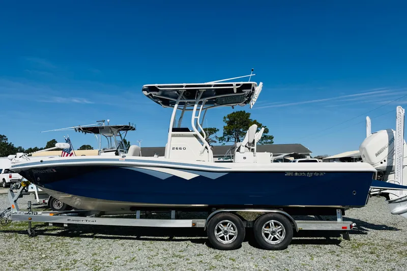 The Image of 2022 Ranger 2660 Bay boat on trailer under clear blue sky. - 1