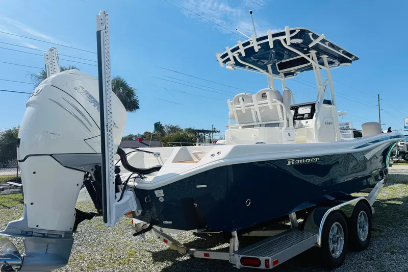 Slide: The Image of 2022 Ranger 2660 Bay boat with Mercury engine on trailer, under clear blue sky. - 3