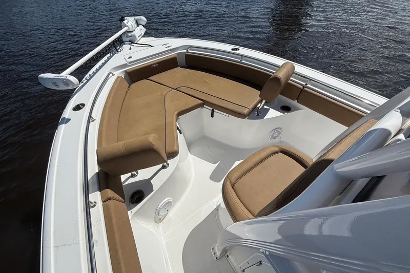 Slide: The Image of 2022 Sea Hunt Ultra 229 boat interior with tan seating, on calm water. - 13