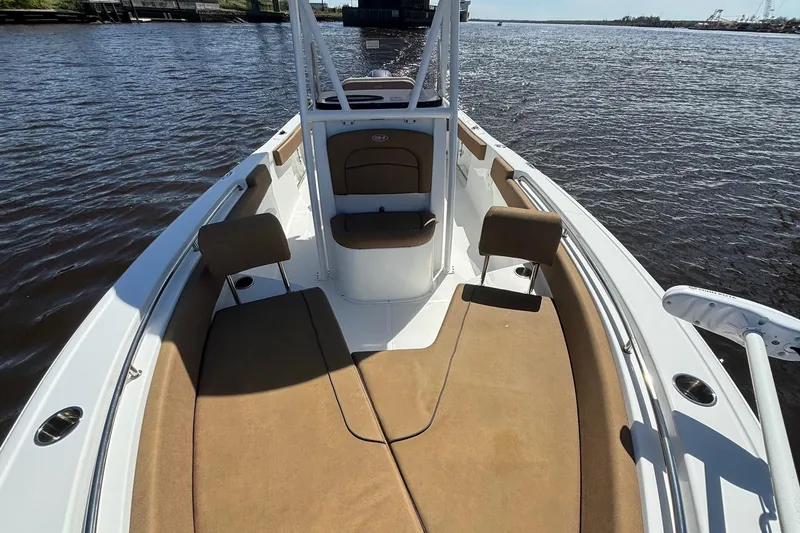 Slide: The Image of 2022 Sea Hunt Ultra 229 boat interior with tan seating on calm water. - 16
