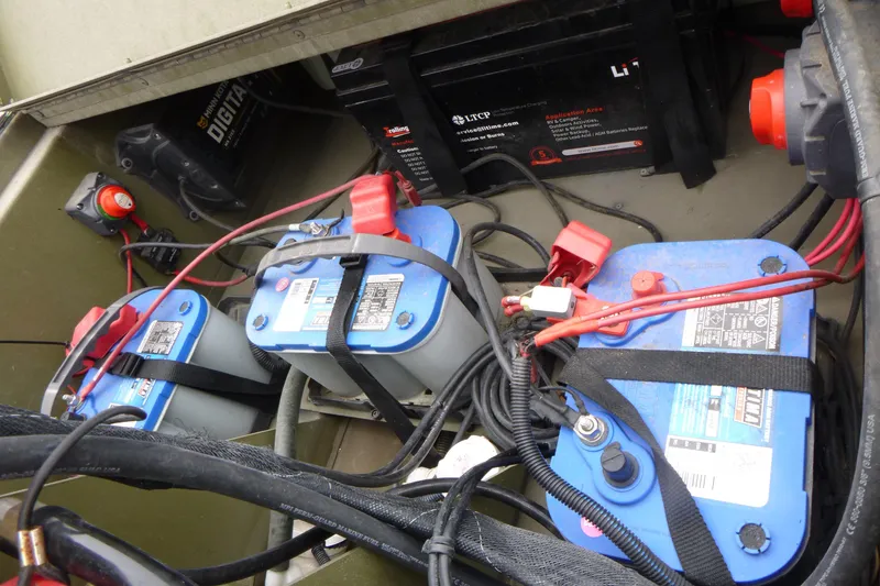 Slide: The Image of 2024 Lowe Roughneck 2070 boat battery compartment with multiple batteries and wiring. - 13