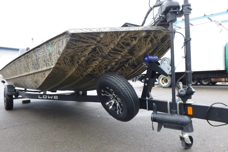 Slide: The Image of 2024 Lowe Roughneck 2070 boat on trailer, featuring camouflage design and sturdy build. - 14