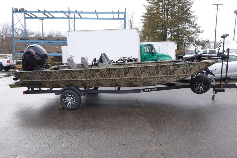 Slide: The Image of 2024 Lowe Roughneck 2070 boat on trailer, camo design, parked outdoors. - 15