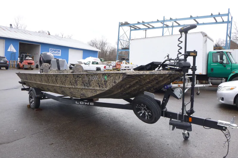Slide: The Image of 2024 Lowe Roughneck 2070 boat on trailer, camo design, parked outdoors. - 17