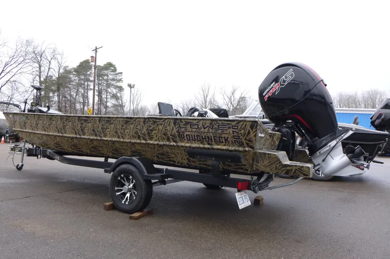 Slide: The Image of 2024 Lowe Roughneck 2070 boat with camouflage design on a trailer, featuring a powerful outboard motor. - 2
