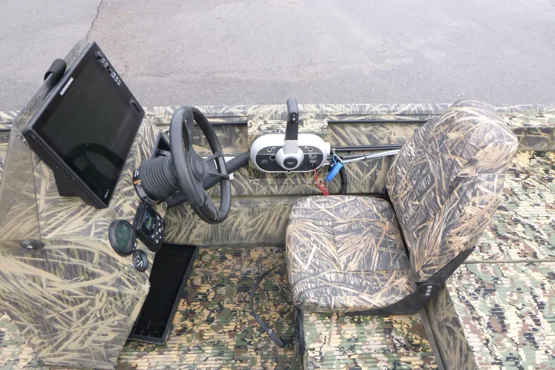 Slide: The Image of 2024 Lowe Roughneck 2070 boat interior with camouflage seating and steering console. - 25
