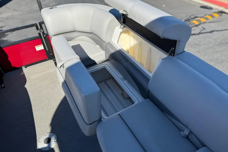 Slide: The Image of 2023 Regency 250 DL3 pontoon boat with open storage compartments and gray seating. - 14