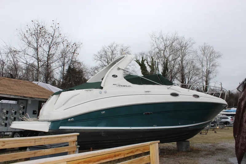 Slide: The Image of 2005 Sea Ray Sundancer 280 boat on land, surrounded by trees and a wooden fence. - 2