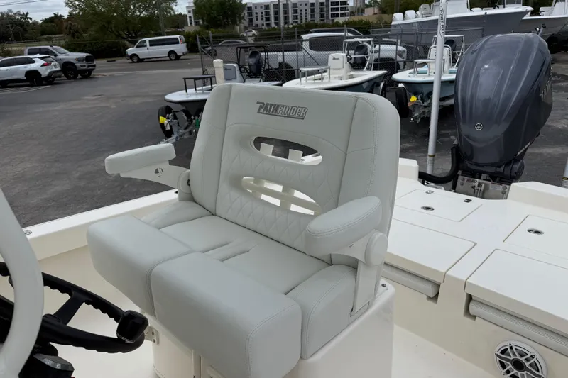Slide: The Image of 2023 Pathfinder 2600 TRS boat seat with armrests and steering wheel in a marina setting. - 17