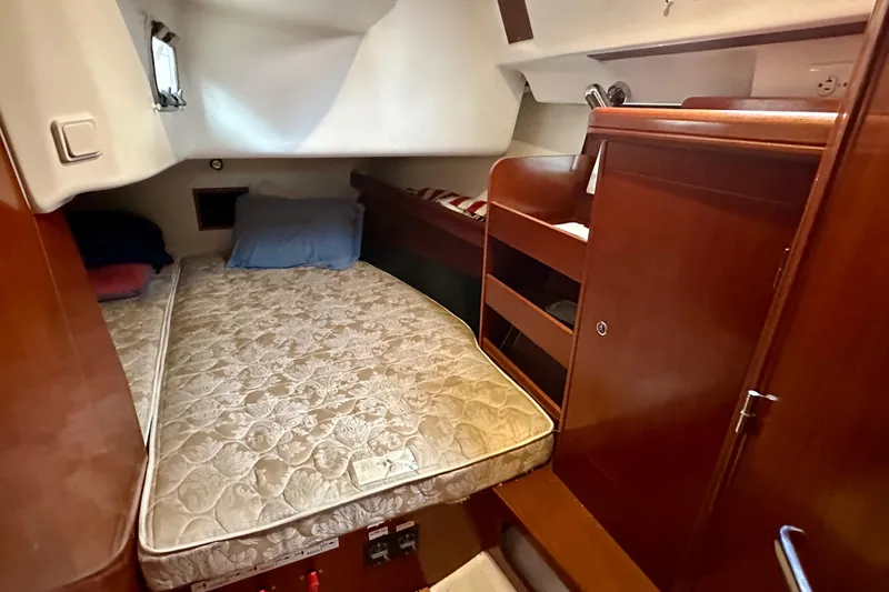 Slide: The Image of 2005 Beneteau Oceanis Clipper 423 cabin with bed, wooden storage, and porthole window. - 21