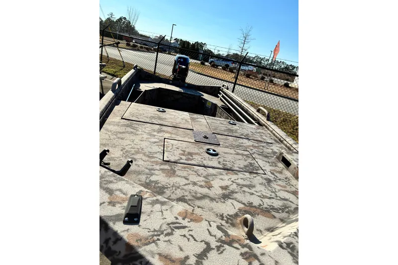 Slide: The Image of Camouflage-patterned 2025 Excel Eclipse boat deck with storage compartments and motor, outdoors. - 3