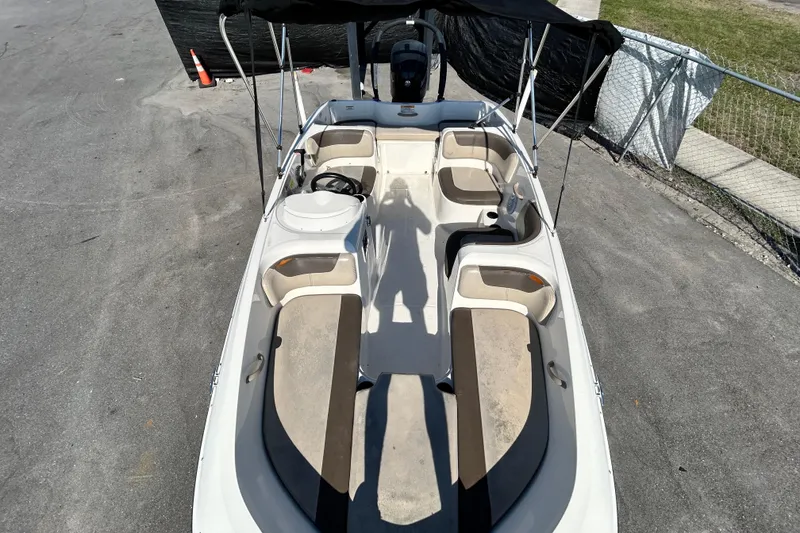 Slide: The Image of 2017 Bayliner Element E16 boat interior with seating and steering wheel, parked on pavement. - 25