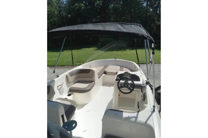 Slide: The Image of 2017 Bayliner Element E16 boat with canopy, steering wheel, and seating, parked outdoors. - 3