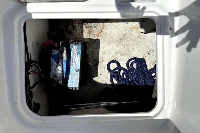 Slide: The Image of 2017 Bayliner Element E16 storage compartment with marine battery and blue rope. - 51