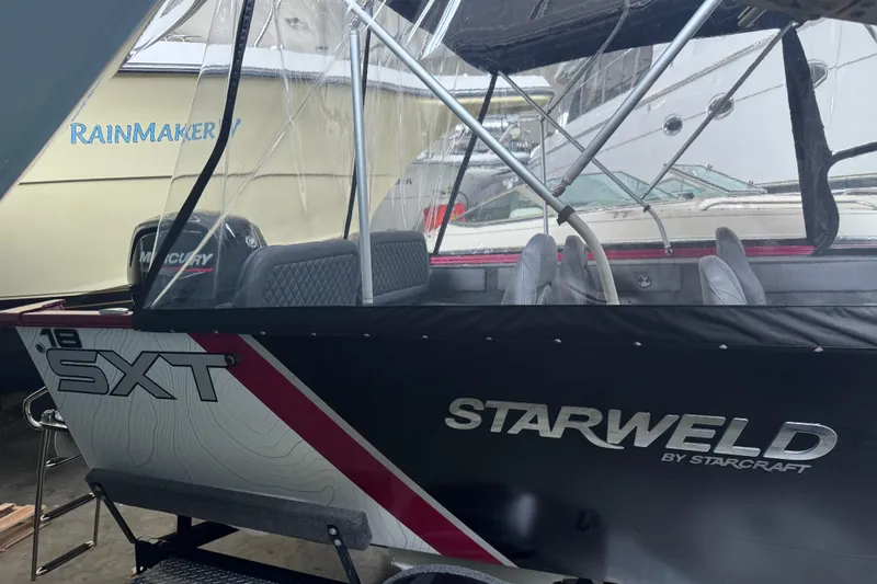 Slide: The Image of 2026 Starweld 18 SXT boat with Mercury engine, docked indoors. - 27