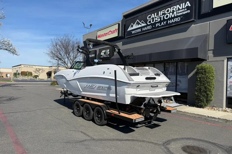 Slide: The Image of 2025 MB B52 25 Alpha boat on trailer outside California Custom store. - 3