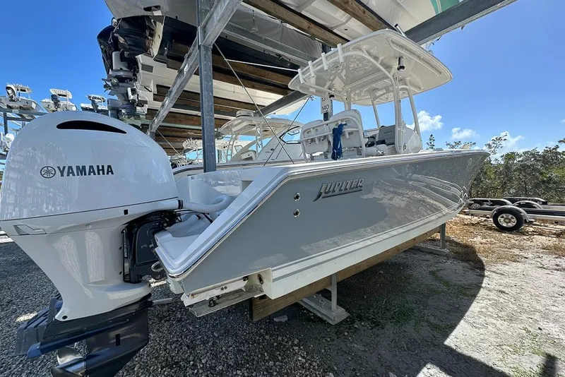 Slide: The Image of 2018 Jupiter 26 FS boat with Yamaha engine, parked outdoors under a clear blue sky. - 4
