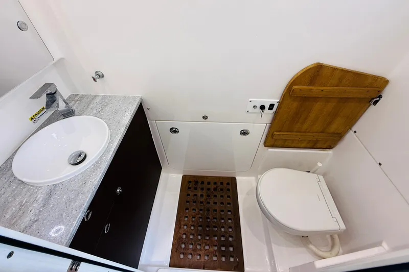 Slide: The Image of 2021 Everglades 395 Center Console bathroom with sink, toilet, and wooden accents. - 40