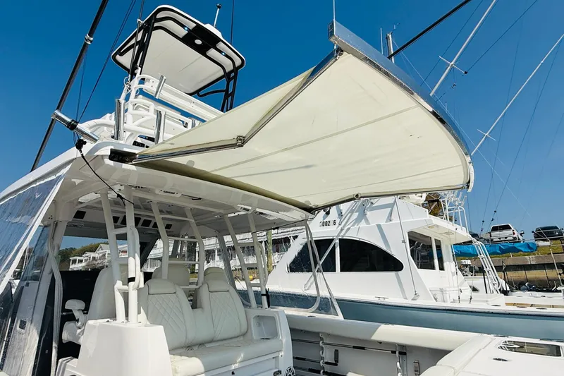 Slide: The Image of 2021 Everglades 395 Center Console boat with canopy, docked under clear blue sky. - 47