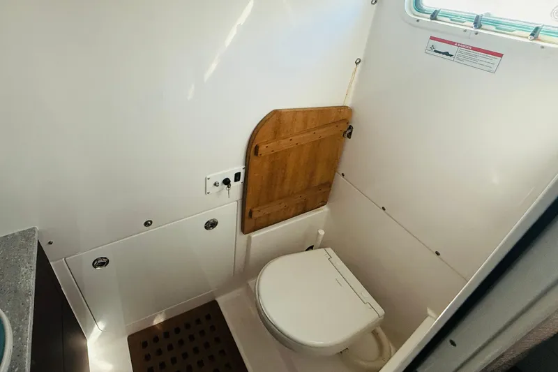 Slide: The Image of Interior of 2021 Everglades 395 Center Console boat bathroom with toilet and wooden accents. - 8