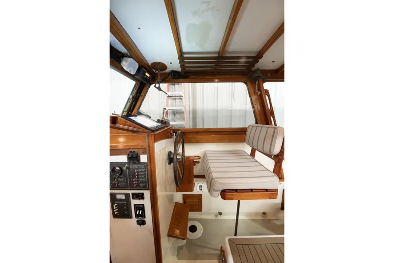Slide: The Image of 1986 Dyer Hardtop boat interior with wooden helm, striped seating, and control panel. - 14