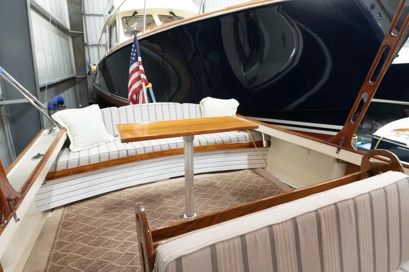 Slide: The Image of 1986 Dyer Hardtop boat interior with striped seating and wooden table in a marina. - 17