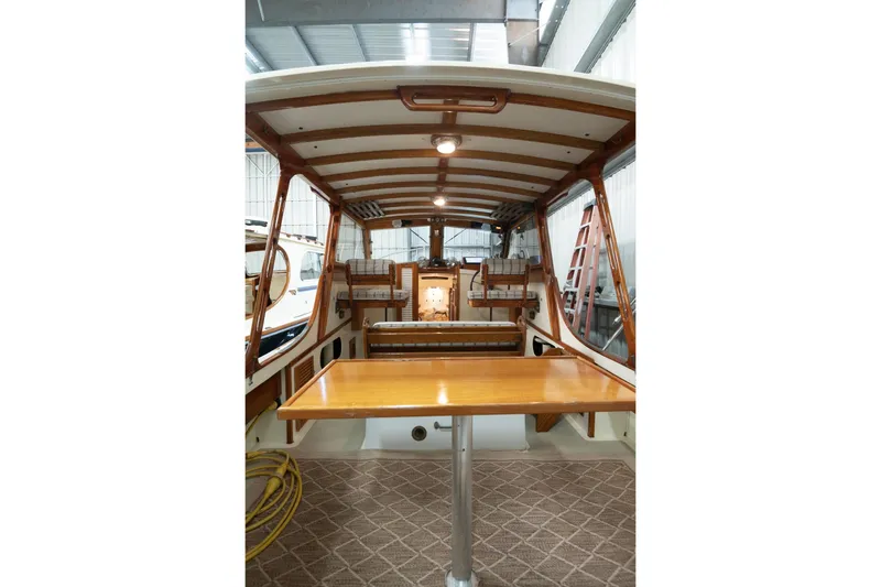 Slide: The Image of 1986 Dyer Hardtop boat interior with wooden table and seating, under a covered deck. - 20