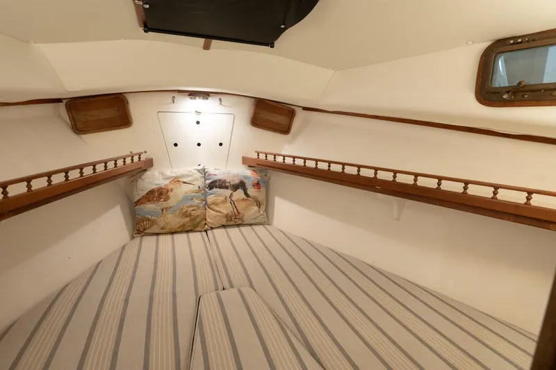 Slide: The Image of Cozy cabin interior of 1986 Dyer Hardtop boat with striped bedding and decorative pillows. - 5