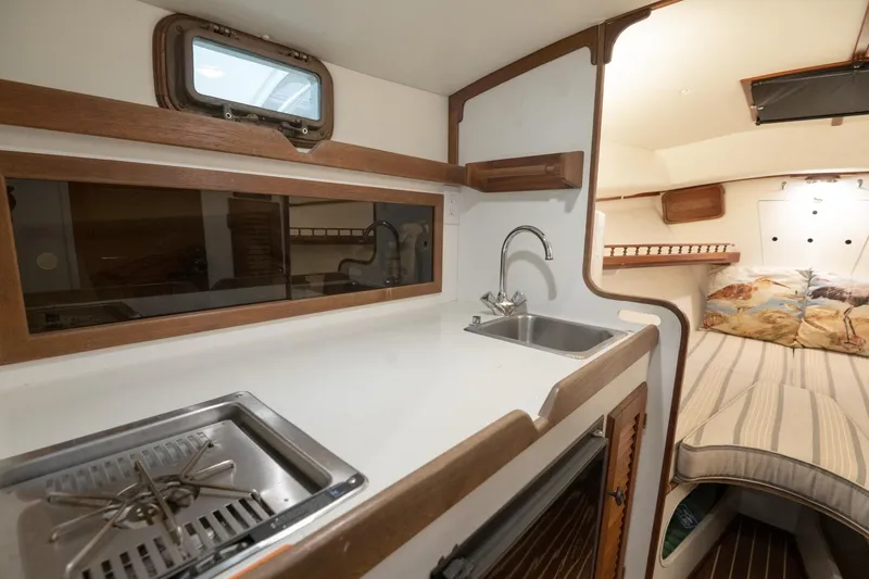 Slide: The Image of 1986 Dyer Hardtop boat interior with kitchenette, sink, and cozy sleeping area. - 6