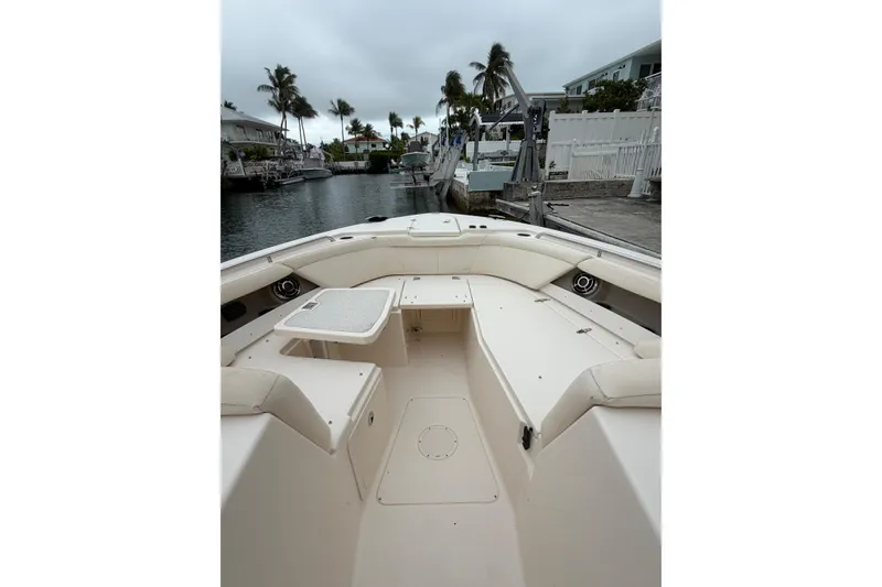 Slide: The Image of 2015 Grady-White Freedom 335 boat interior with seating and table, docked by palm trees. - 16