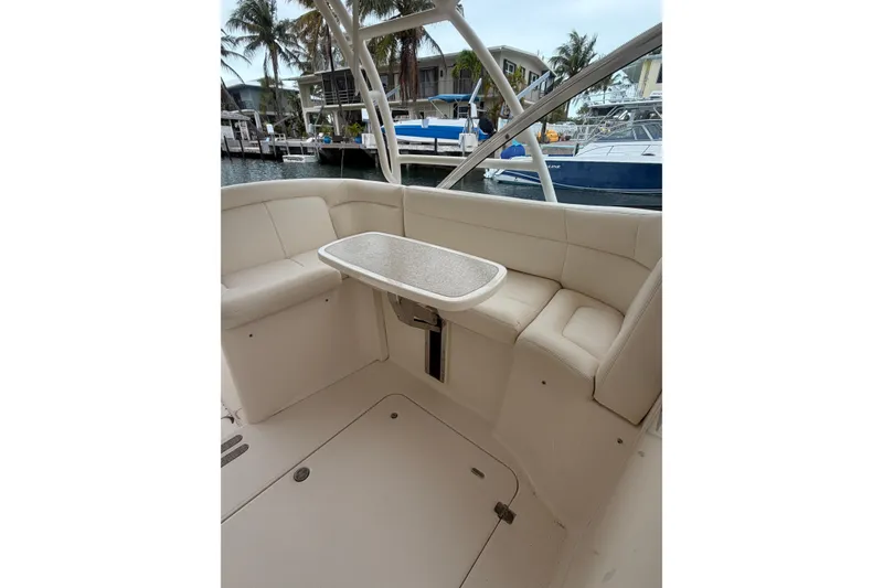 Slide: The Image of 2015 Grady-White Freedom 335 boat interior with seating and table, docked near palm trees. - 7