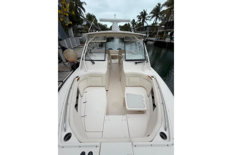 Slide: The Image of 2015 Grady-White Freedom 335 boat interior with seating and table, docked by palm trees. - 8