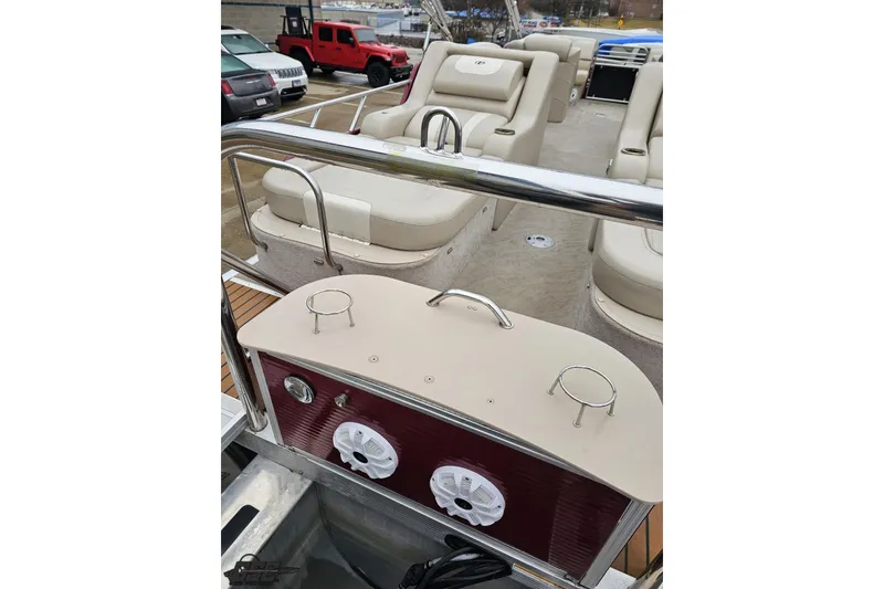 Slide: The Image of 2012 Tahoe Pontoon Vision 25' with beige seating and speaker system in a parking lot. - 14