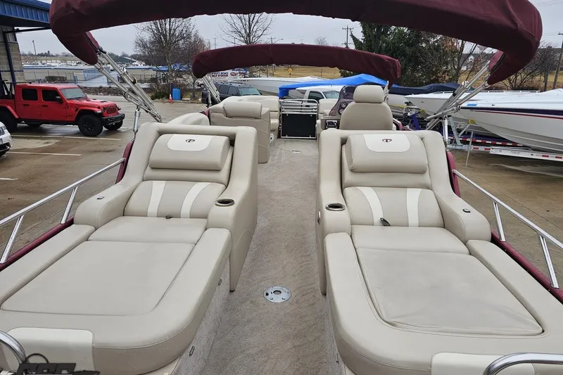 Slide: The Image of 2012 Tahoe Pontoon Vision 25' with luxurious seating and maroon canopy in a marina. - 16