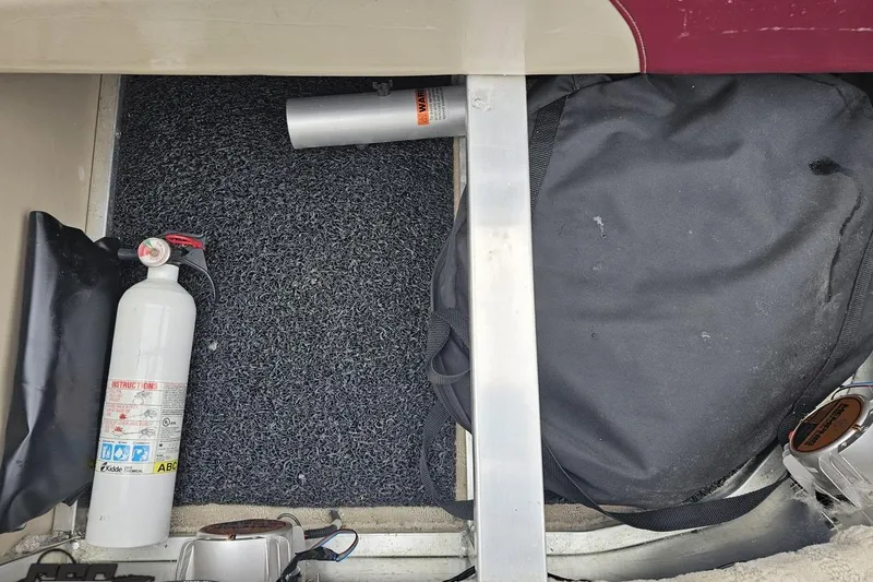 Slide: The Image of Storage compartment of a 2012 Tahoe Pontoon Vision 25' with fire extinguisher and backpack. - 59