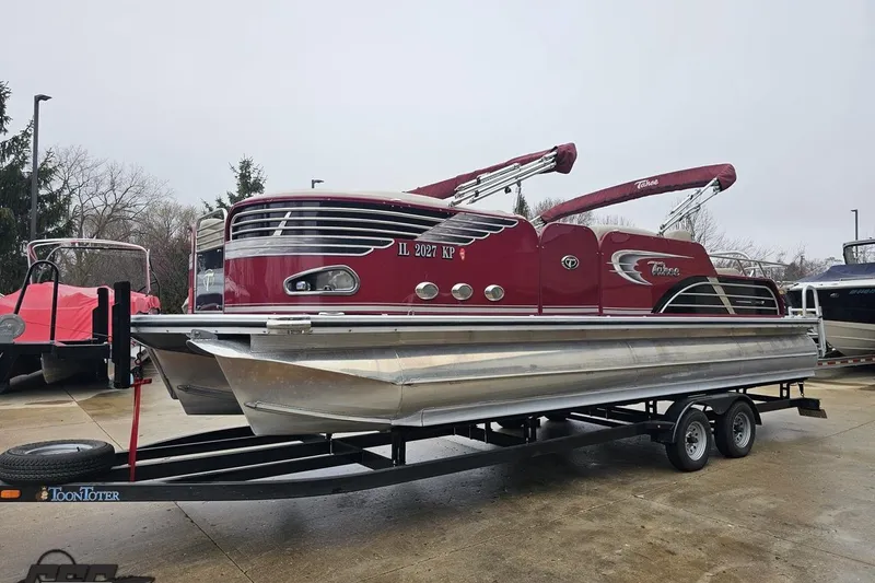 Slide: The Image of 2012 Tahoe Pontoon Vision 25' boat on trailer, red exterior, parked outdoors. - 7