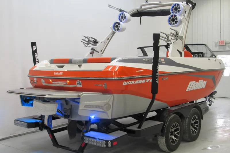 Slide: The Image of 2021 Malibu Wakesetter 21 VLX boat in a showroom, vibrant orange and white design. - 2
