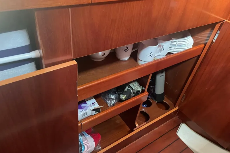 Slide: The Image of Wooden cabinet interior on 2005 Beneteau Oceanis 42CC yacht, featuring mugs and storage shelves. - 10
