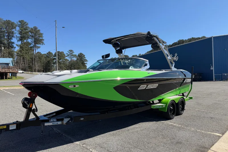 The Image of 2015 MB B-52 23 Widebody boat with green and black design on trailer. - 1