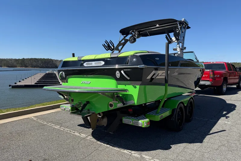 Slide: The Image of 2015 MB B-52 23 Widebody boat in vibrant green and black, parked near a lake. - 5