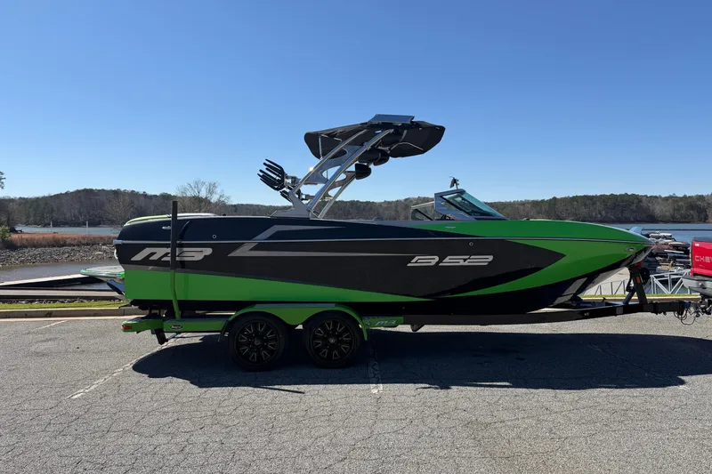 Slide: The Image of 2015 MB B-52 23 Widebody boat in green and black, parked near a lake. - 6