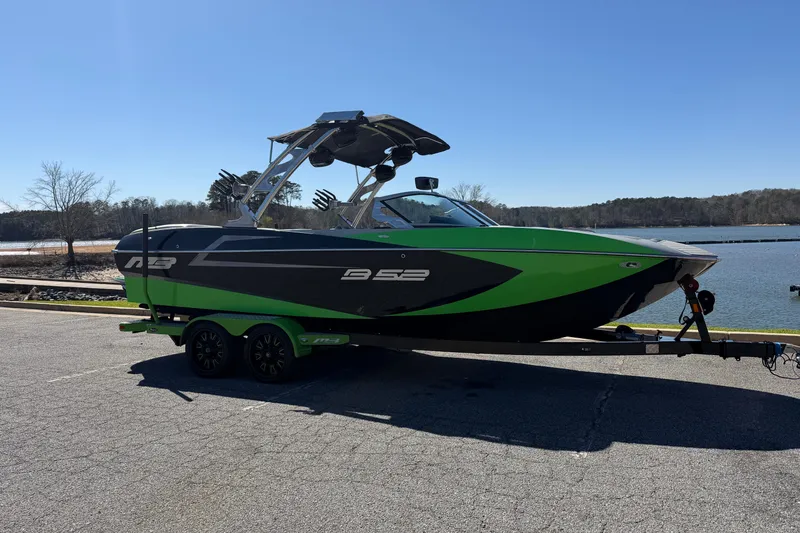 Slide: The Image of 2015 MB B-52 23 Widebody boat on trailer by a lake under clear sky. - 7