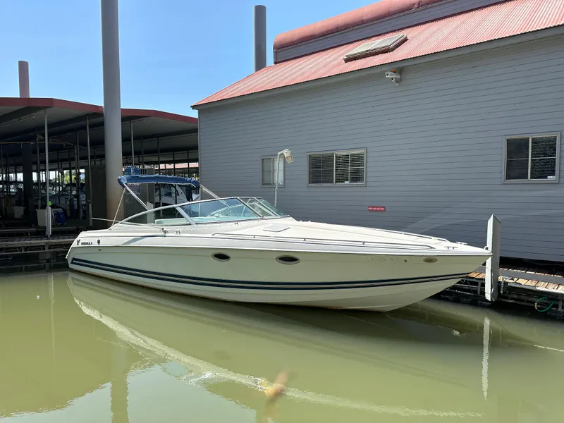 The Image of 2000 Formula 330 SS boat docked beside a building on calm water. - 0