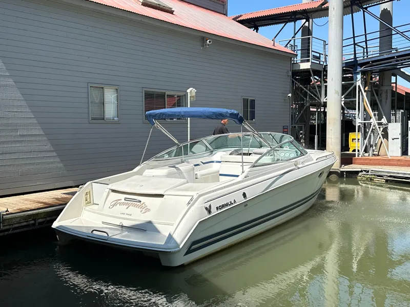 Slide: The Image of 2000 Formula 330 SS boat docked by a building, featuring sleek design and blue canopy. - 49