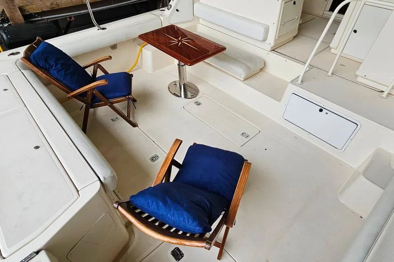 Slide: The Image of 1996 Tiara Yachts 4300 Open cockpit with wooden chairs and table, featuring blue cushions. - 11