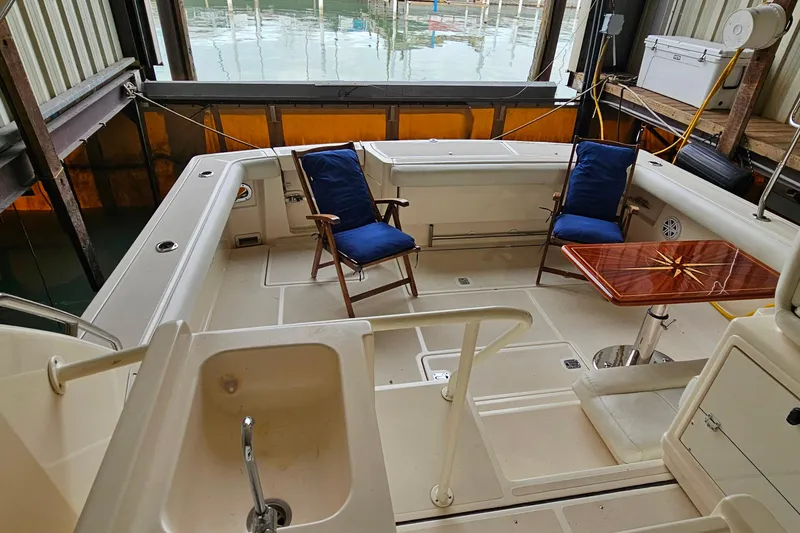 Slide: The Image of 1996 Tiara Yachts 4300 Open cockpit with chairs, table, and sink in a marina setting. - 22