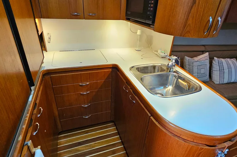 Slide: The Image of 1996 Tiara Yachts 4300 Open galley with wooden cabinetry and stainless steel sink. - 27
