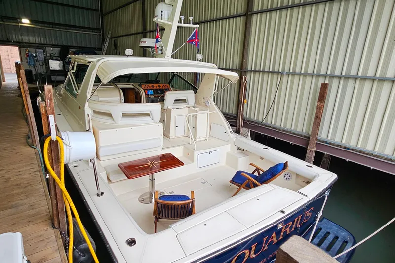 Slide: The Image of 1996 Tiara Yachts 4300 Open docked in a covered marina, featuring a spacious deck. - 5